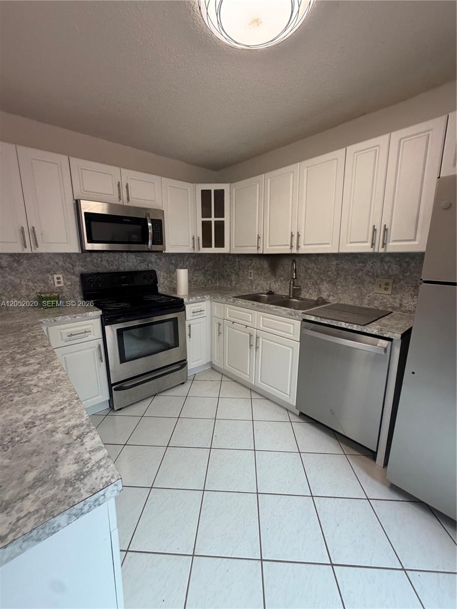 A kitchen features white cabinets, stainless steel appliances, and gray speckled laminate countertops — 2563 CAMELOT # 2563, Cooper City FL 33026, COOPER CITY, FL