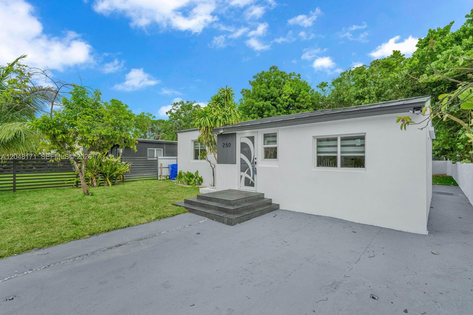 A white single-story house with a gray roof and a front concrete driveway — 250 NW 45 ST, Miami FL 33127, MIAMI, FL