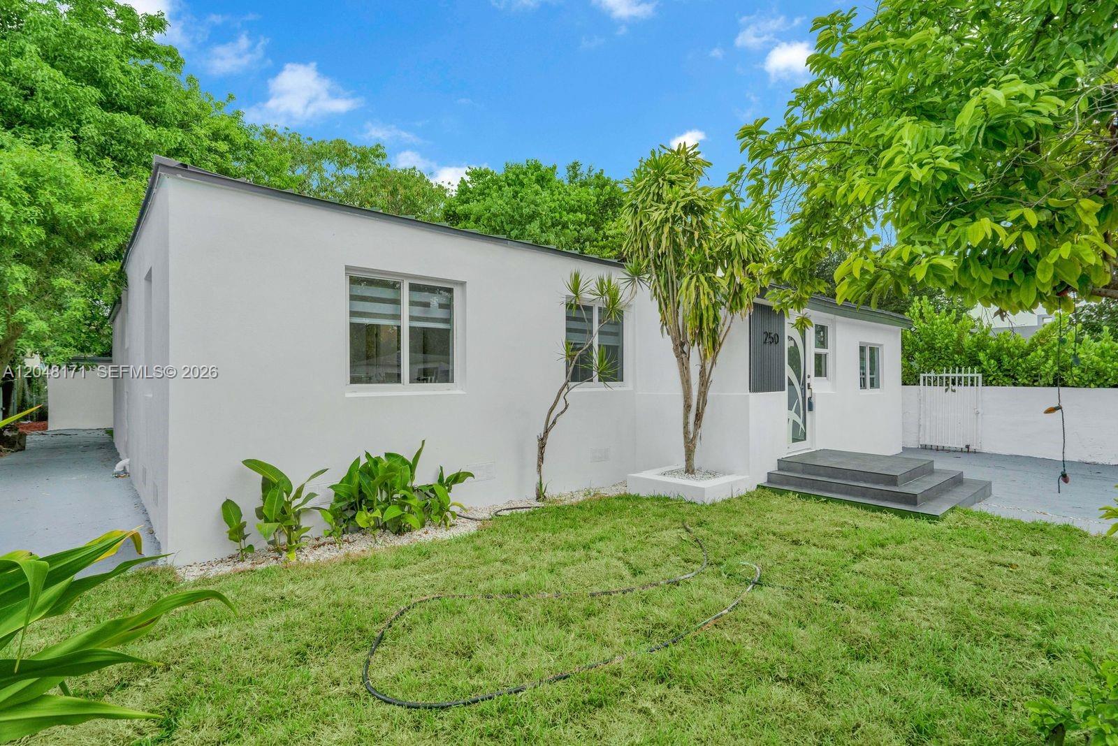 A white, single-story house with a front lawn, a small porch, and mature trees — 250 NW 45 ST, Miami FL 33127, MIAMI, FL