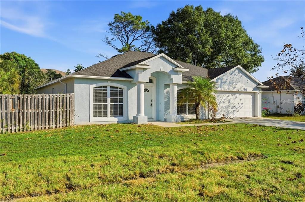 A single-story house with a light blue stucco exterior, a two-car garage, and white columns — 1158 PERPIGNAN COURT, KISSIMMEE, FL