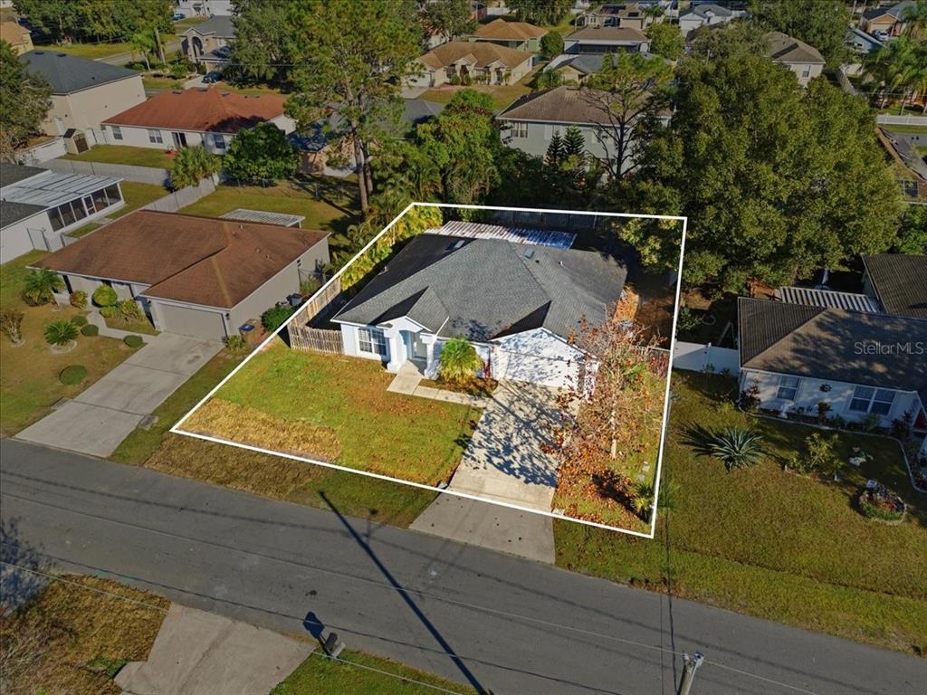 An aerial view shows a single-story house with a gray roof and a concrete driveway — 1158 PERPIGNAN COURT, KISSIMMEE, FL