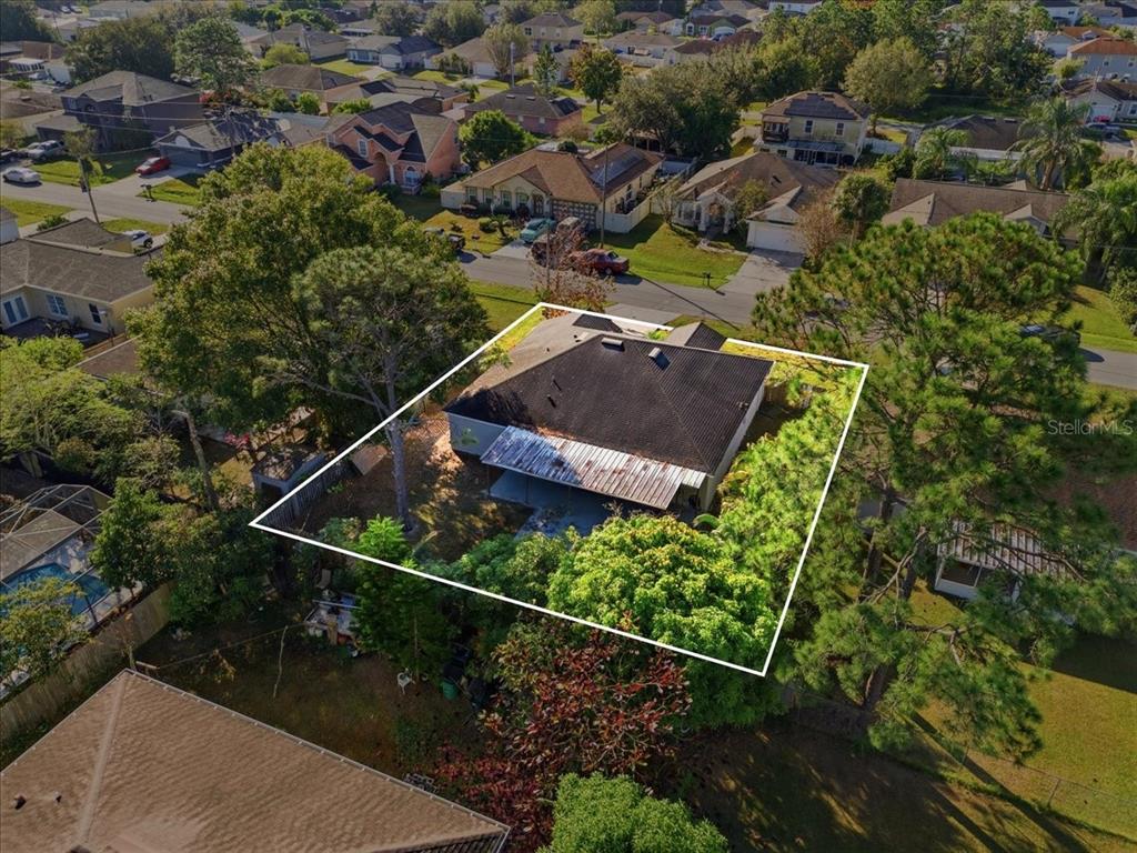 An aerial view shows a single-story house with a dark roof and a metal-covered patio — 1158 PERPIGNAN COURT, KISSIMMEE, FL