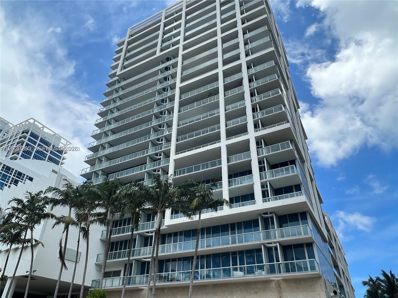 A tall, modern residential high-rise building features glass balconies and palm trees in the foreground — 6799 Collins Ave # 1501, Miami Beach FL 33141, MIAMI BEACH, FL