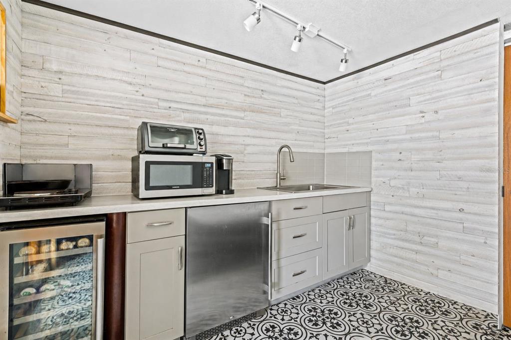 A kitchenette features light gray cabinets, stainless steel appliances, a sink, and patterned floor tiles — 860 12TH AVENUE N, ST PETERSBURG, FL