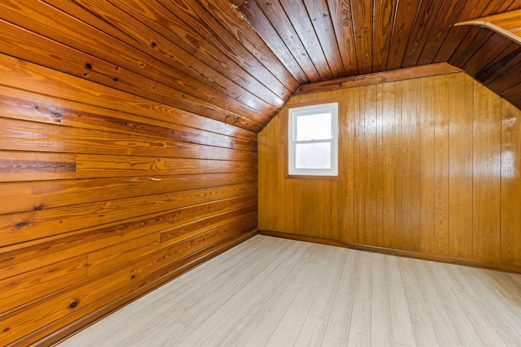 An attic room features wood-paneled walls and ceiling with light-colored wood-look flooring and a window — 860 12TH AVENUE N, ST PETERSBURG, FL