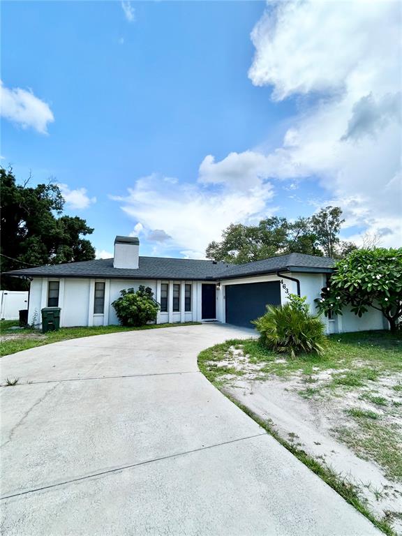 A single-story house with a white exterior, dark roof, and a large concrete driveway — 4633 BROOKSDALE DRIVE, SARASOTA, FL