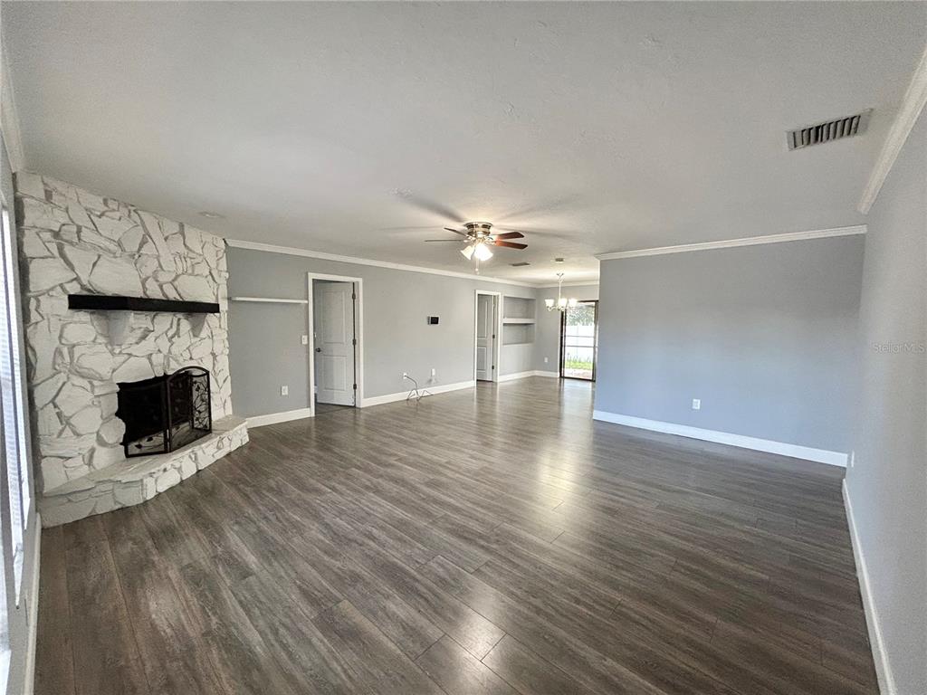 A living room features gray walls, wood-look flooring, and a white stone corner fireplace — 4633 BROOKSDALE DRIVE, SARASOTA, FL