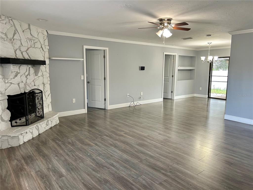 A living room features gray walls, wood-look flooring, a white stone fireplace, and two doorways — 4633 BROOKSDALE DRIVE, SARASOTA, FL