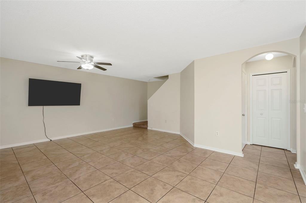 An empty room with beige walls, tan tile flooring, a ceiling fan, and a closet — 7361 E BANK DRIVE, TAMPA, FL