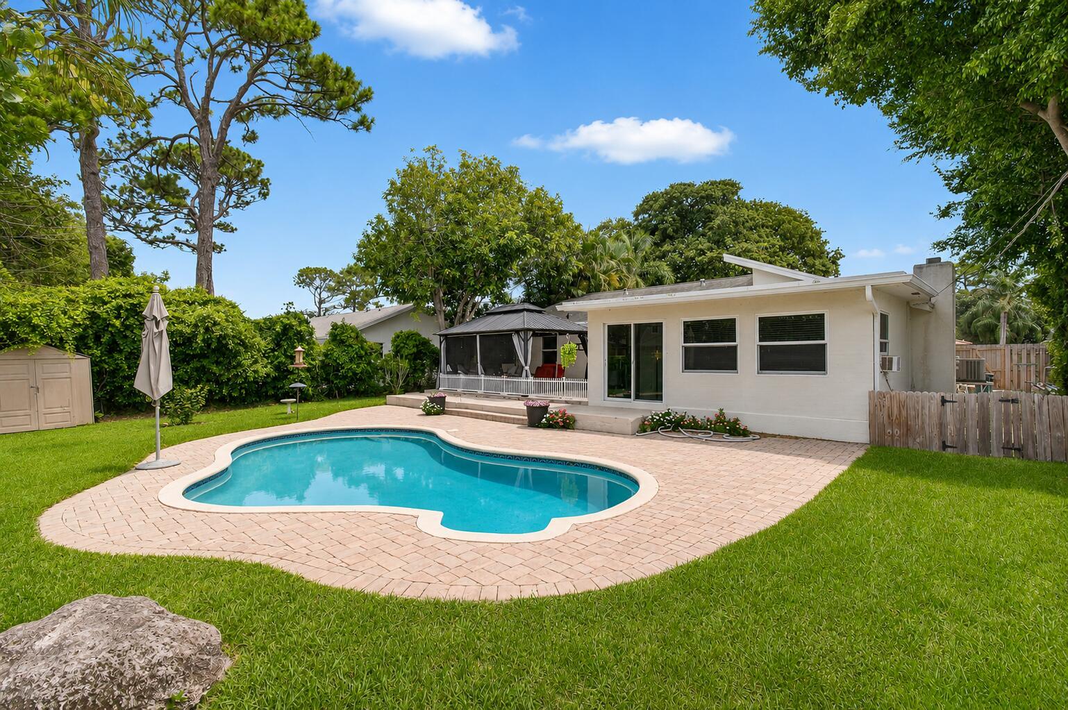 A backyard features a swimming pool, a paved patio, a gazebo, and a white house — 5442 Sunrise Boulevard, Delray Beach FL 33484, DELRAY BEACH, FL