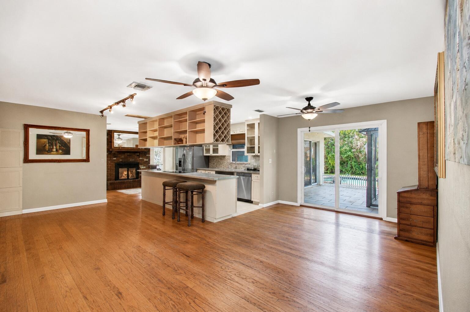 An open-concept living area features hardwood floors, a kitchen island, and sliding glass patio doors — 5442 Sunrise Boulevard, Delray Beach FL 33484, DELRAY BEACH, FL