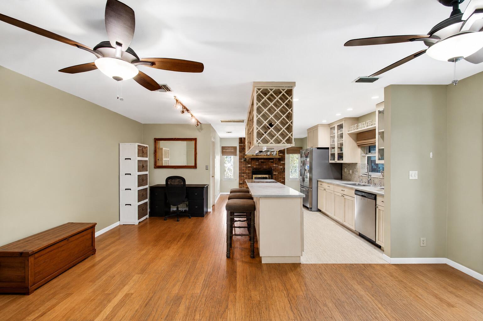 An open-concept kitchen and living area features wood flooring, a central island, and ceiling fans — 5442 Sunrise Boulevard, Delray Beach FL 33484, DELRAY BEACH, FL