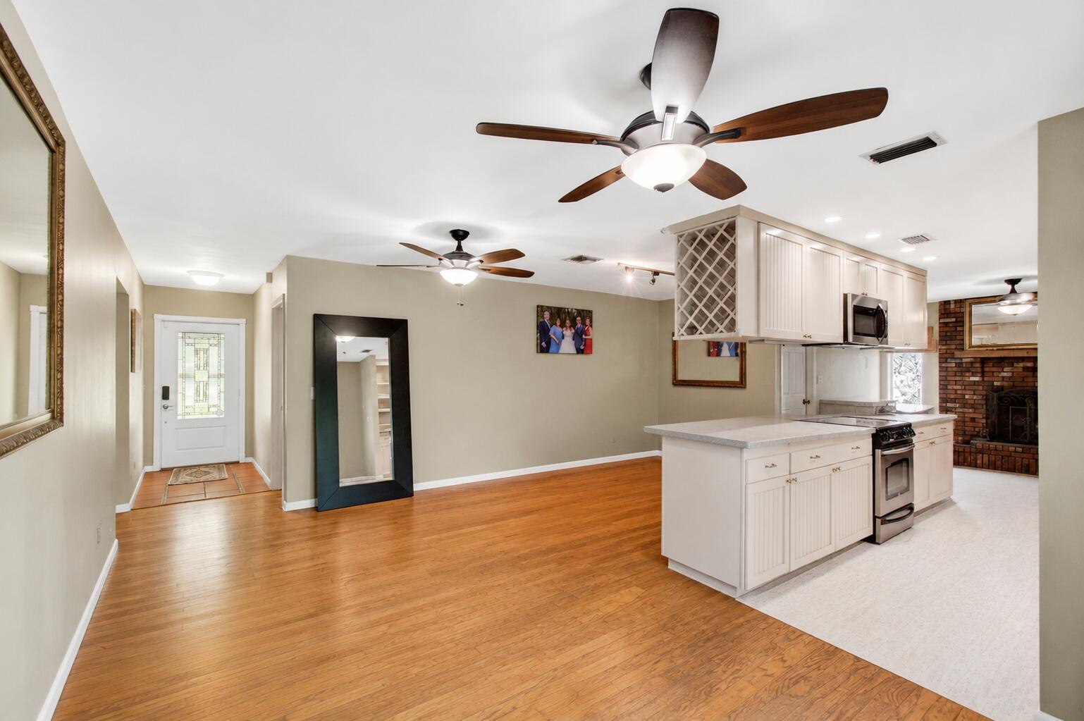 A kitchen with white cabinets and a breakfast bar opens into a living area — 5442 Sunrise Boulevard, Delray Beach FL 33484, DELRAY BEACH, FL