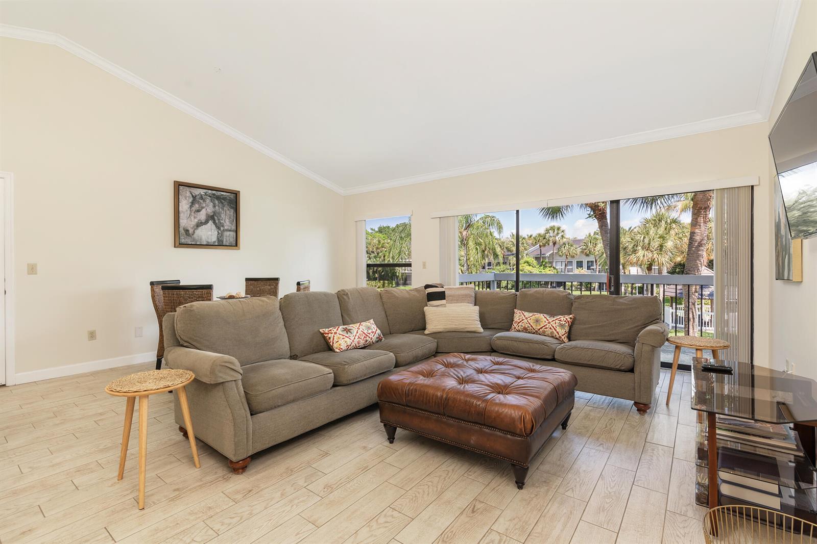 A living room features a large sectional sofa, leather ottoman, and sliding glass balcony doors — 11863 Wimbledon Circle, Wellington FL 33414, WELLINGTON, FL