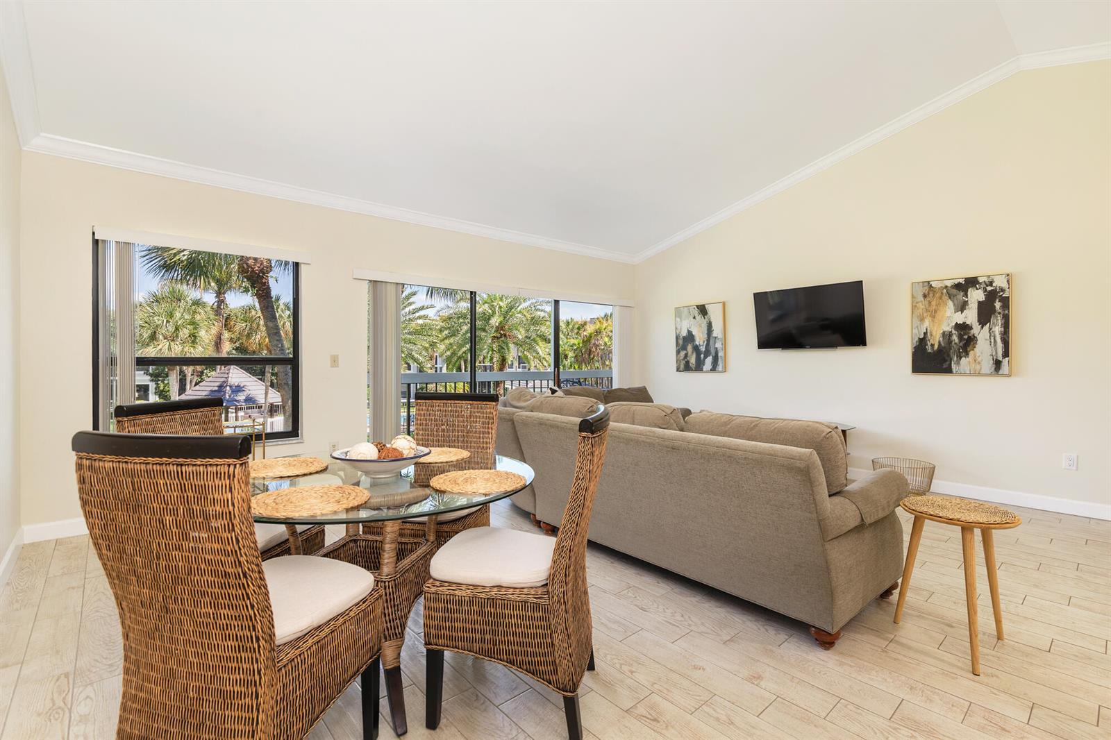 A dining area with a glass table and wicker chairs sits beside a living room — 11863 Wimbledon Circle, Wellington FL 33414, WELLINGTON, FL