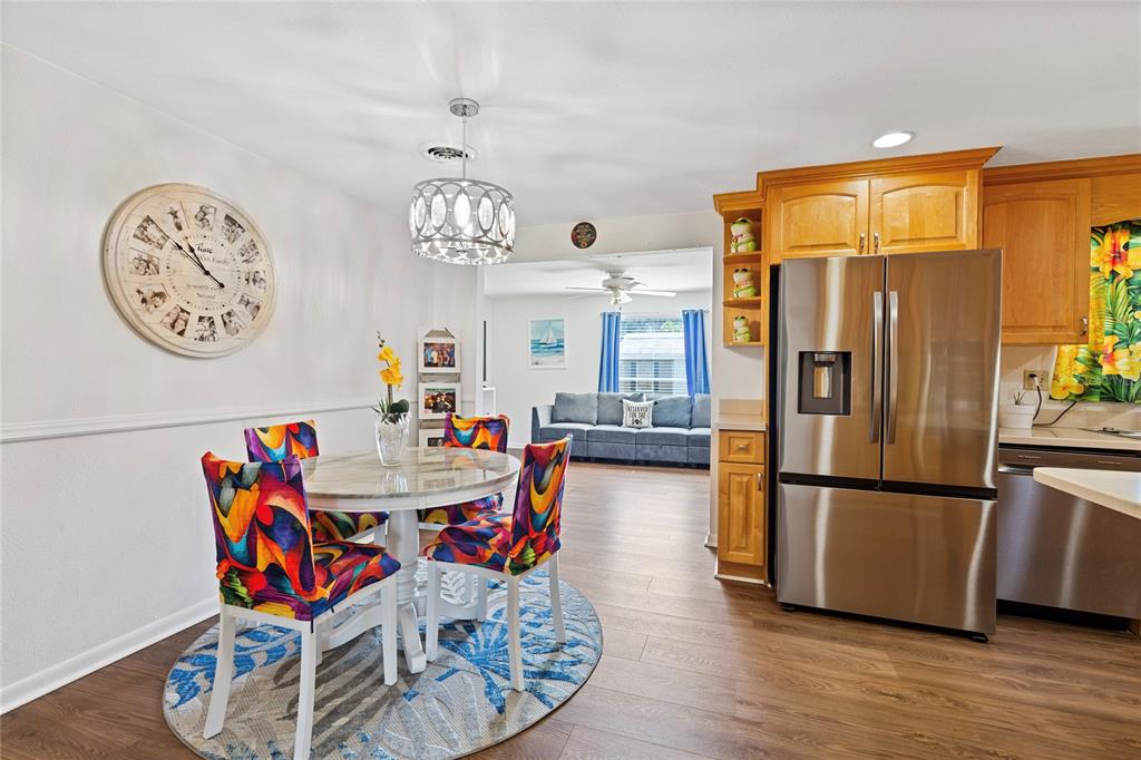 A dining area with a round table and colorful chairs sits adjacent to a kitchen — 5906 CYPRESS STREET, ZEPHYRHILLS, FL