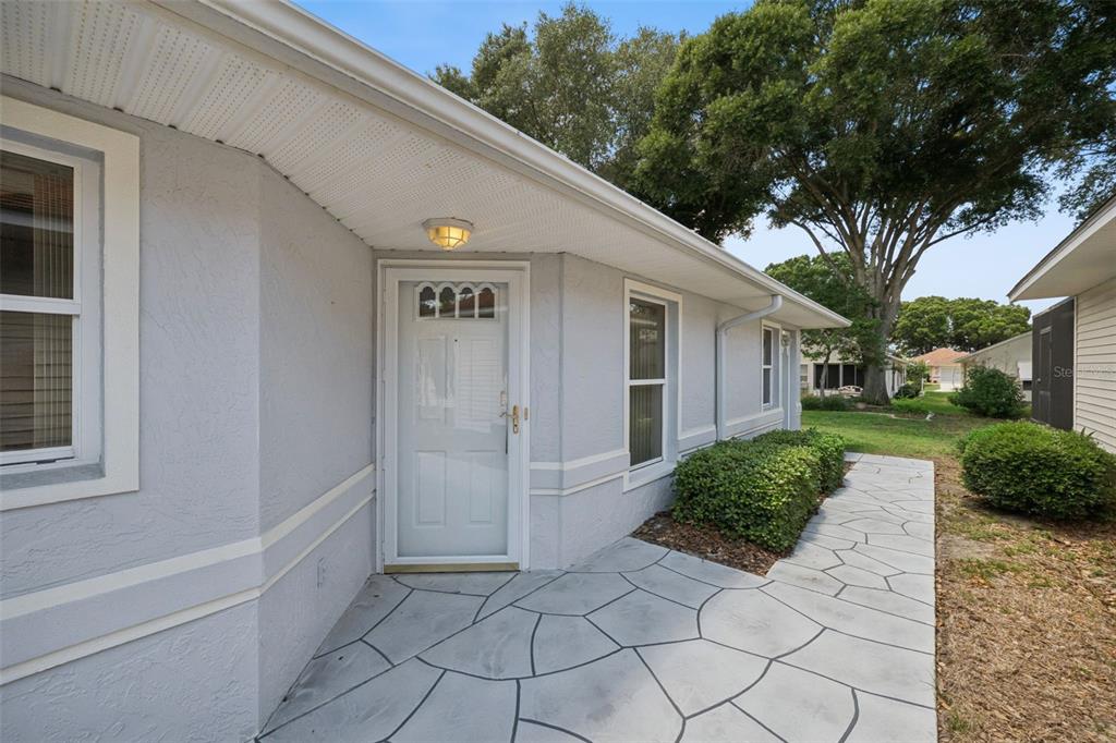 A light gray house exterior features a white front door, stone-patterned patio, and landscaping — 5503 LAVER STREET, LEESBURG, FL