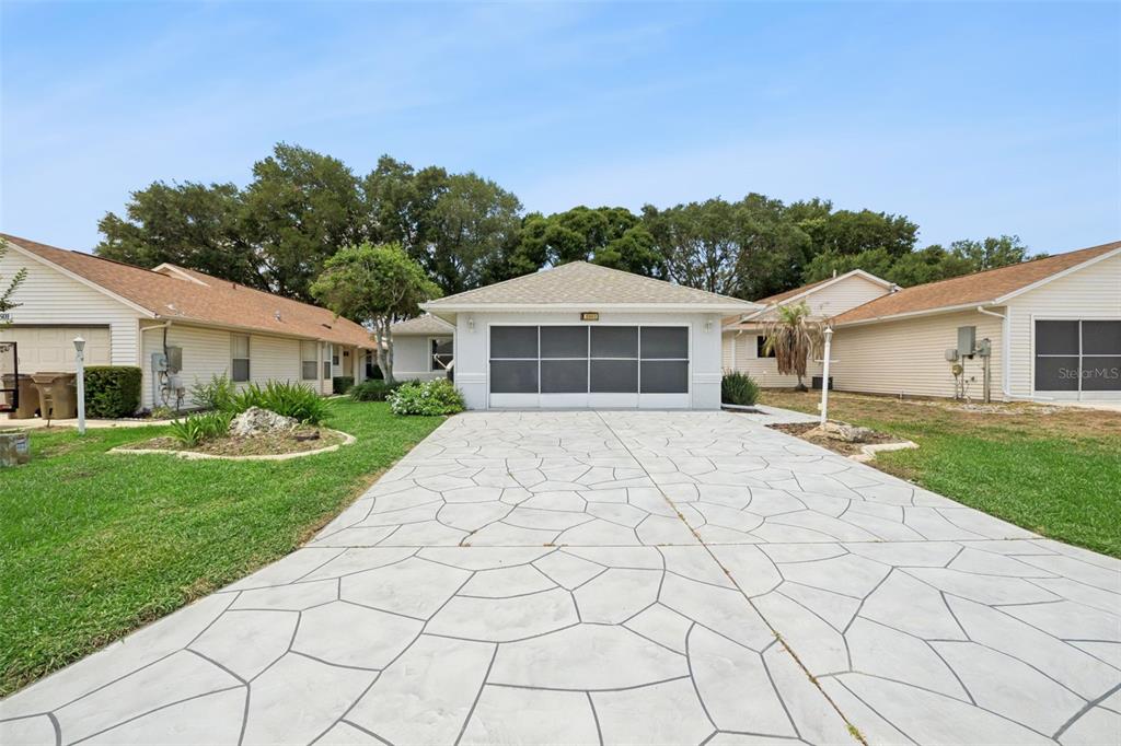 A single-story house with a patterned concrete driveway and a screened-in garage door — 5503 LAVER STREET, LEESBURG, FL