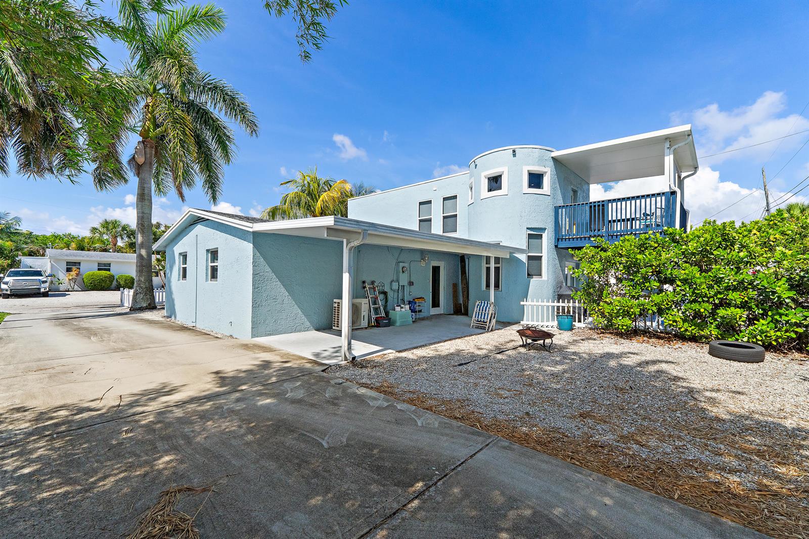 A light blue two-story house with a carport, balcony, and gravel yard under a blue sky — 1779 Len Drive # 1, North Palm Beach FL 33408, NORTH PALM BEACH, FL