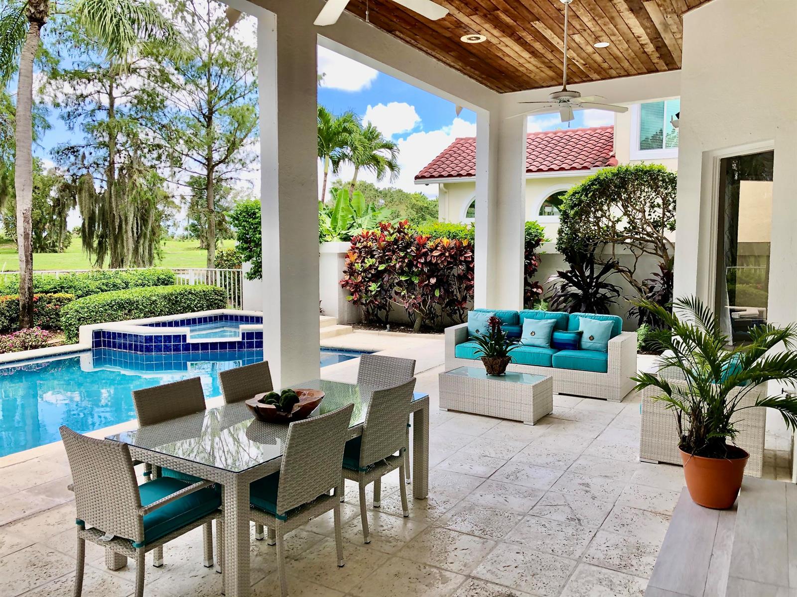 A covered patio features a dining set, outdoor sofa, and a swimming pool with a spa — 2313 Golf Brook Drive, Wellington FL 33414, WELLINGTON, FL