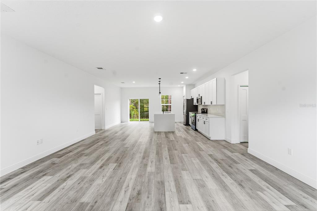 A white vinyl fence encloses a bare, dirt-covered backyard next to a house exterior — 2773 SW 147ST STREET RD, OCALA, FL