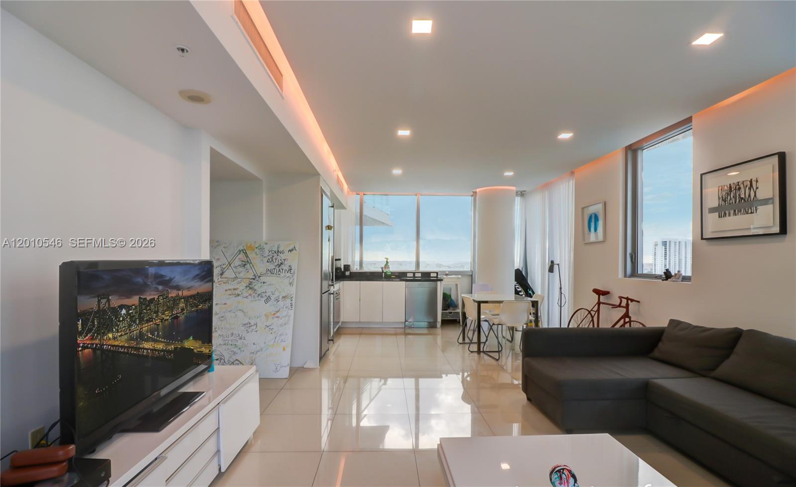 A modern open-concept living area features a kitchen, dining space, and a grey sectional sofa — 92 SW 3rd St # 2410, Miami FL 33130, MIAMI, FL
