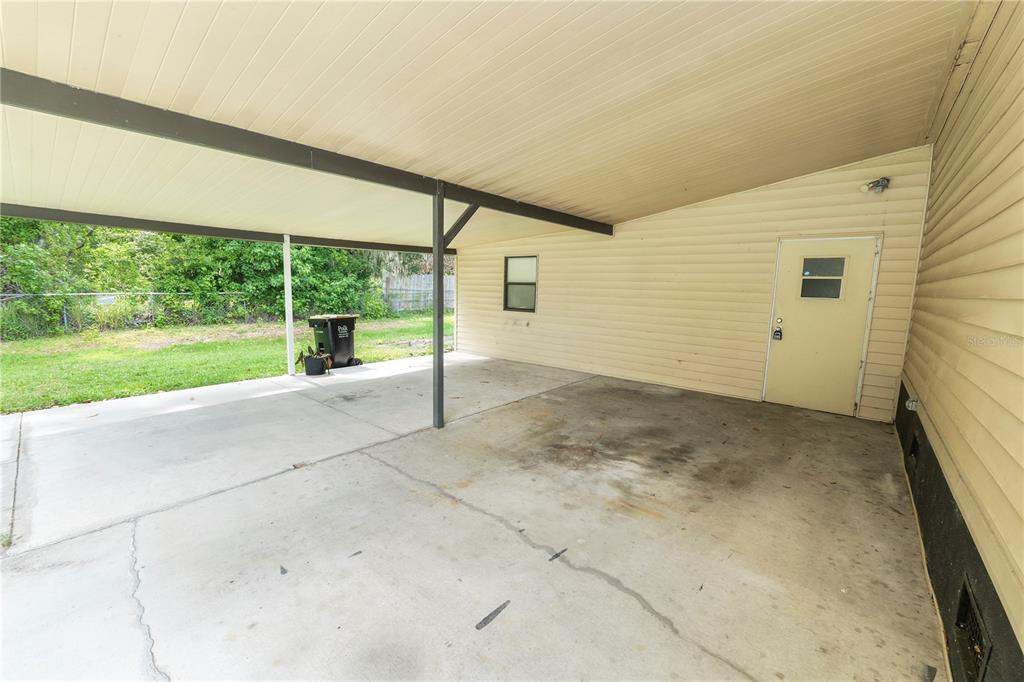 A concrete carport with a beige exterior wall, a single door, and a small window — 3159 HONEOYE TRAIL UNIT 42, LAKELAND, FL