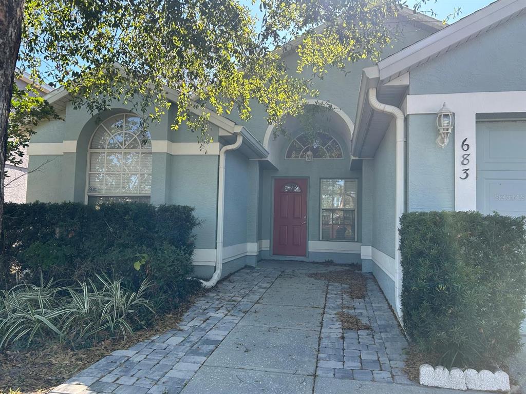A light blue house with a red front door and a paved walkway — 683 RANDON TERRACE, LAKE MARY, FL