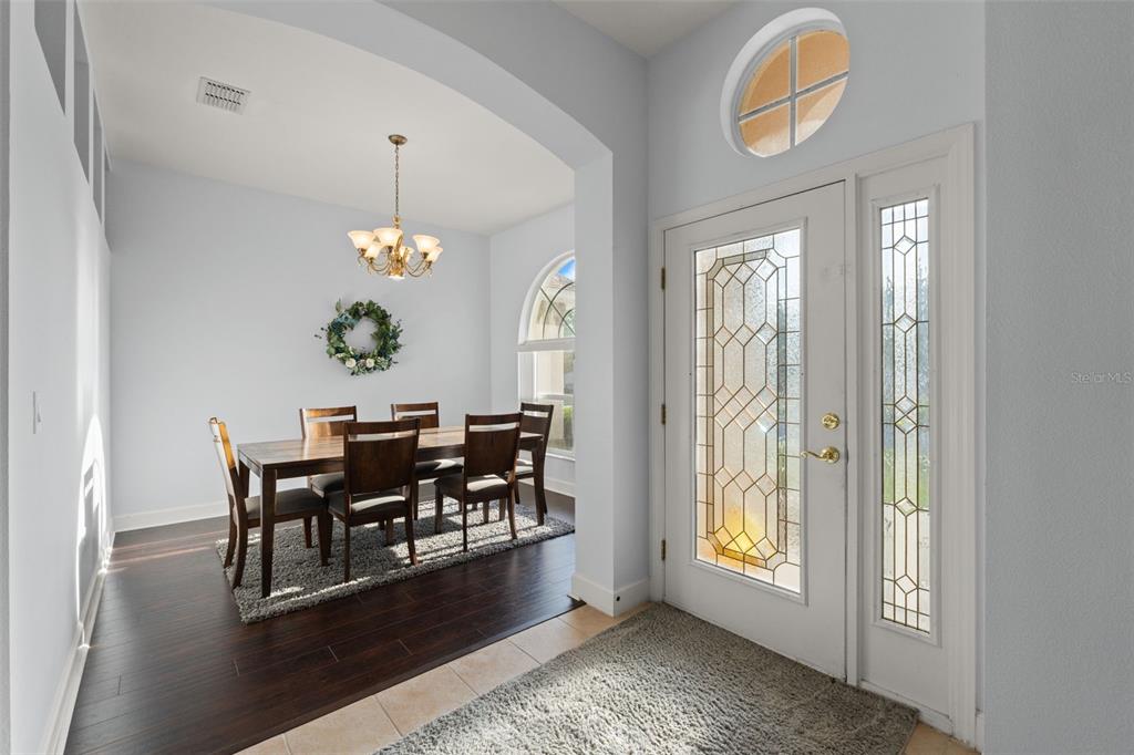 An entryway with tile flooring leads into a dining room featuring dark wood floors — 5683 BRACKENWOOD DRIVE, SPRING HILL, FL