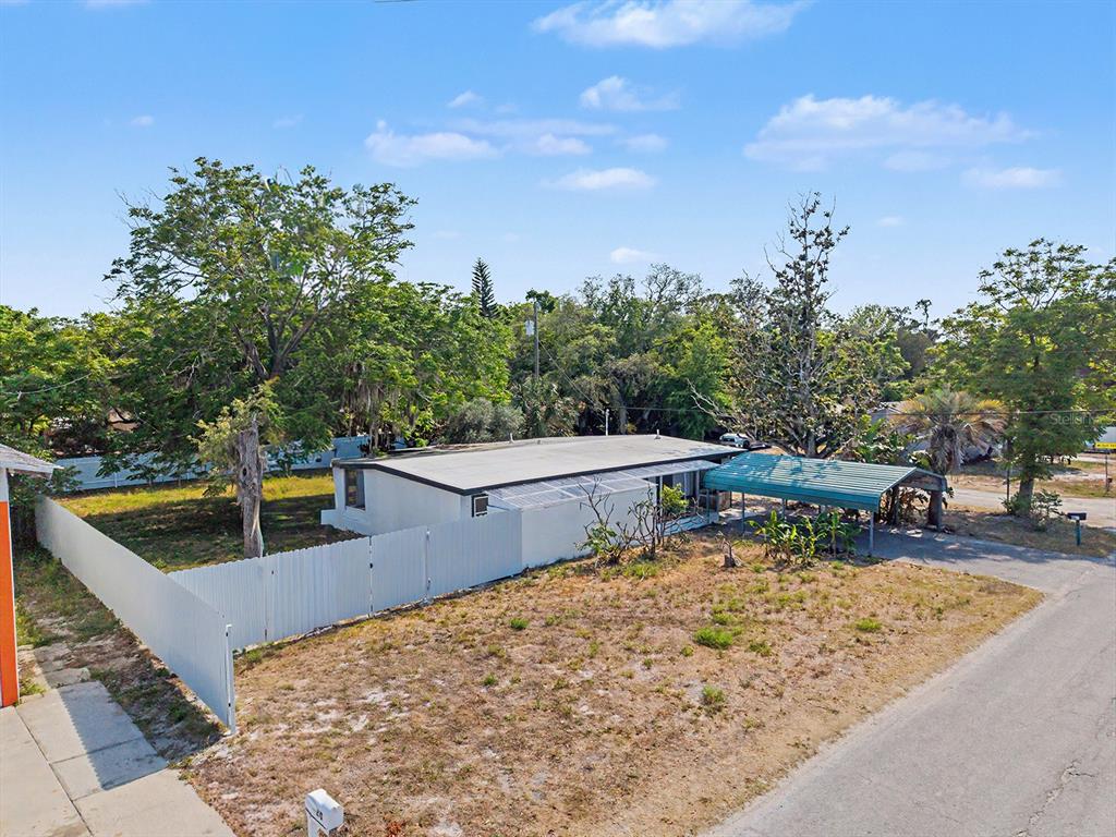An aerial view shows a single-story house with a flat roof and a metal carport — 7708 MARYLAND AVENUE, HUDSON, FL