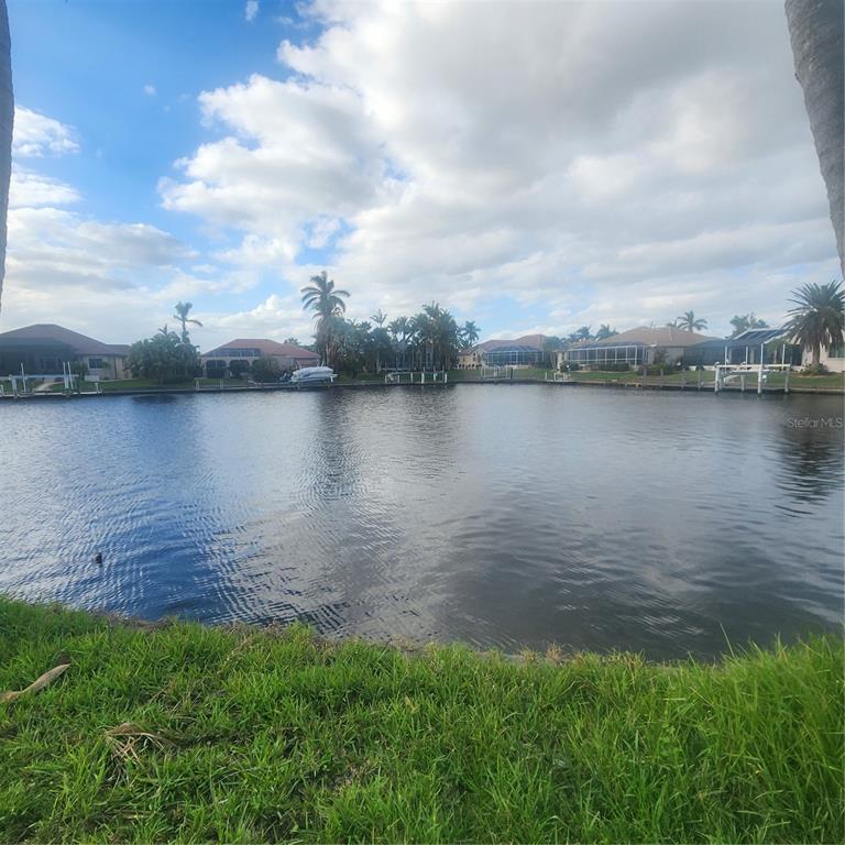 A view of a canal lined with houses, palm trees, and private boat docks — 3907 MADRID COURT, PUNTA GORDA, FL