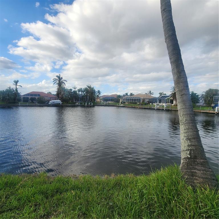 A view of a canal from a grassy bank with palm trees and waterfront houses — 3907 MADRID COURT, PUNTA GORDA, FL