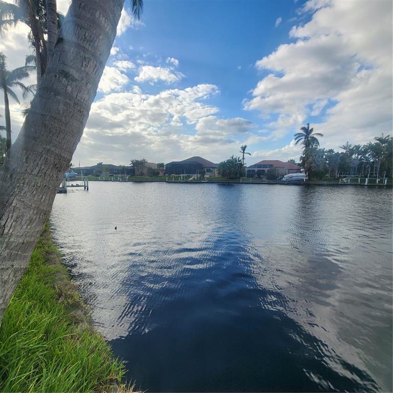 A view of a canal with houses, palm trees, and boat docks under a sky — 3907 MADRID COURT, PUNTA GORDA, FL