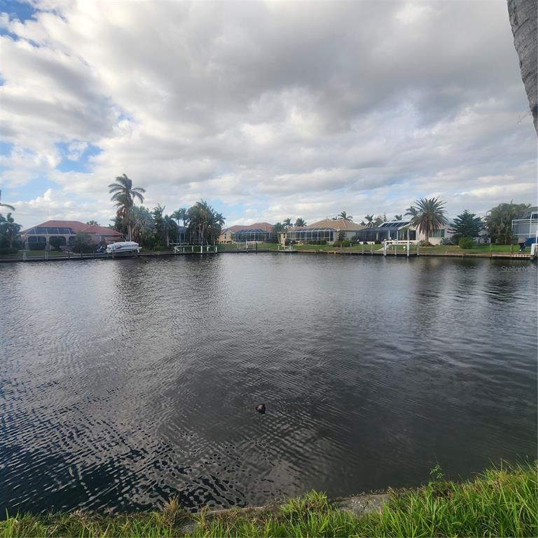 A view of a canal with houses and palm trees along the opposite bank — 3907 MADRID COURT, PUNTA GORDA, FL