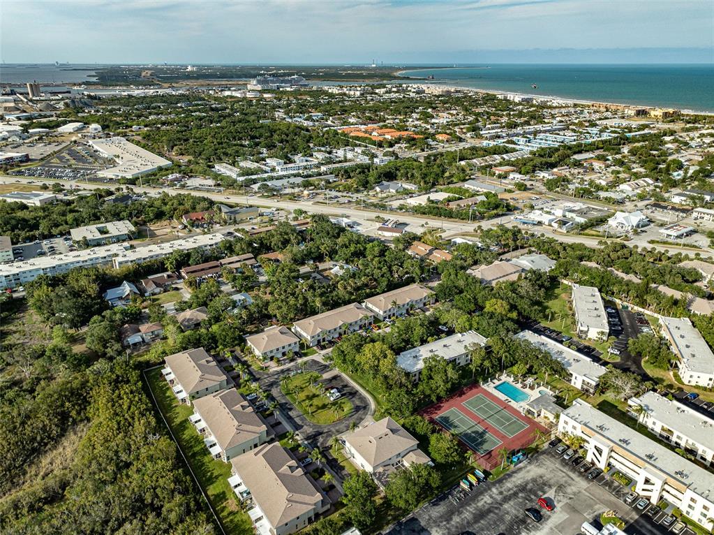 An aerial view shows a multi-building apartment complex situated along a large body of water — 200 INTERNATIONAL DRIVE UNIT 505, CAPE CANAVERAL, FL