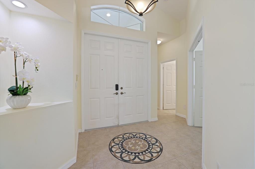A bright entryway features double white doors, tile flooring with a circular inlay, and lighting — 4211 64TH AVENUE E, SARASOTA, FL