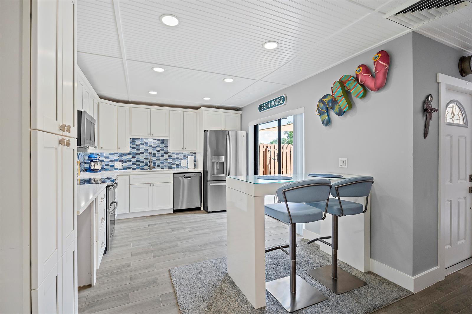 A kitchen with white cabinets, blue mosaic tile backsplash, stainless appliances, and a breakfast bar — 6163 SE Riverboat Drive # 1018, Stuart FL 34997, STUART, FL