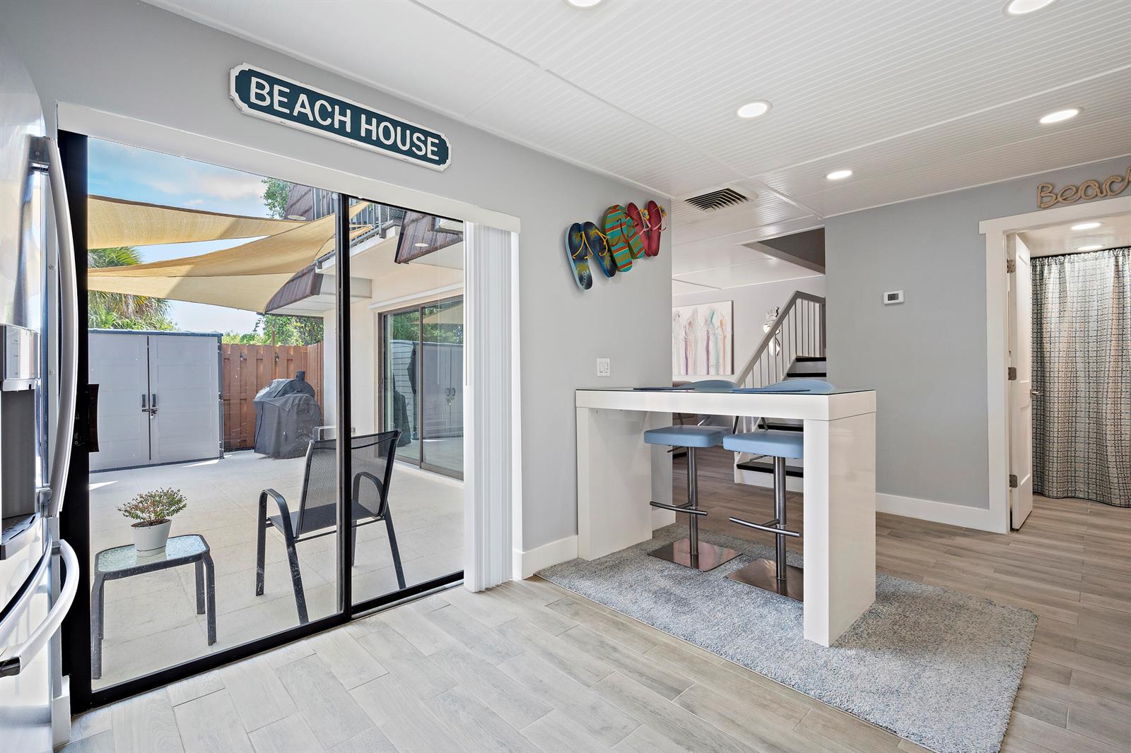 A bright room features a breakfast bar, sliding glass doors to a patio, and beach-themed decor — 6163 SE Riverboat Drive # 1018, Stuart FL 34997, STUART, FL