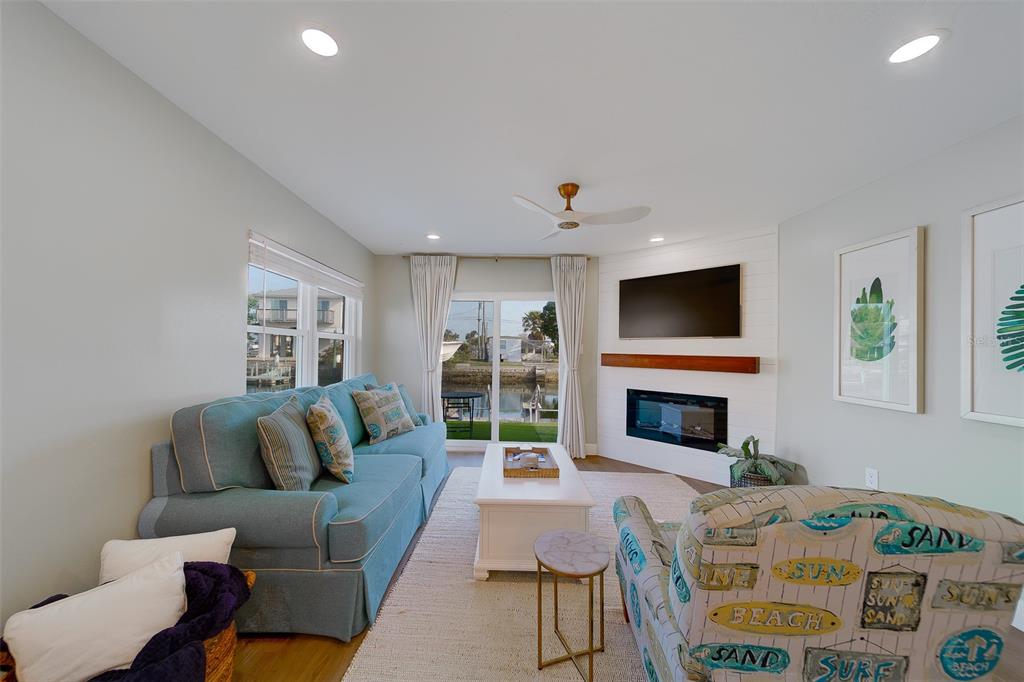 A living room features a blue sofa, patterned armchair, fireplace, and sliding doors to water — 6403 LONNIE LEE LANE, HUDSON, FL
