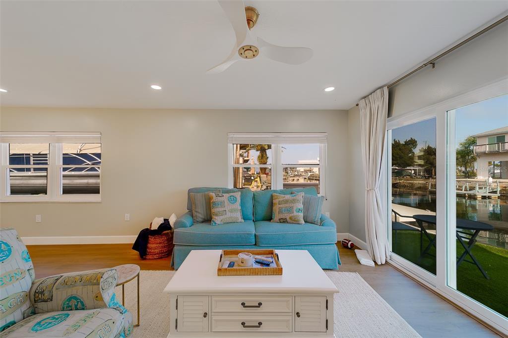 A living room features a blue sofa, white coffee table, and sliding glass doors overlooking water — 6403 LONNIE LEE LANE, HUDSON, FL
