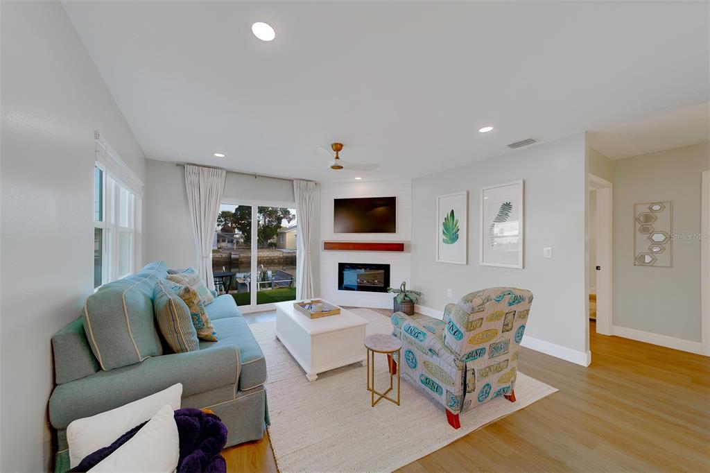 A living room features a blue sofa, patterned armchair, fireplace, and sliding glass doors — 6403 LONNIE LEE LANE, HUDSON, FL