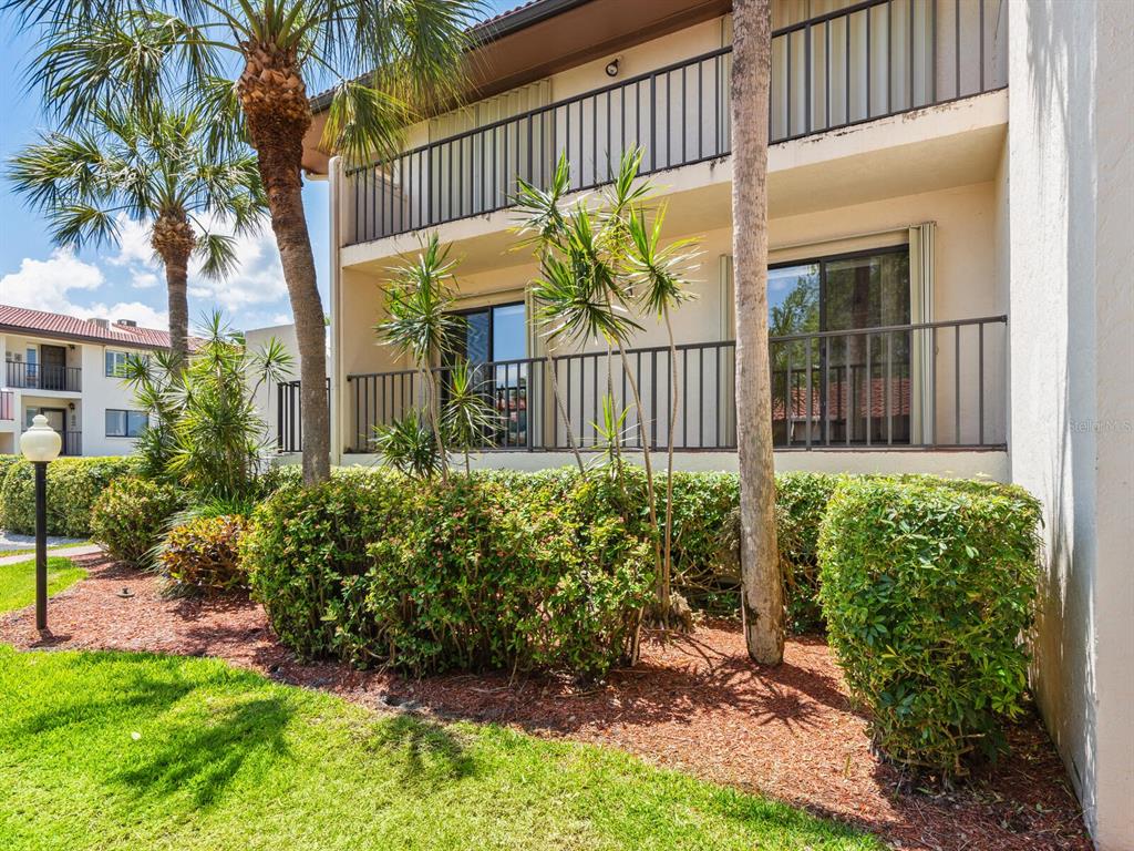 A two-story apartment building exterior features balconies, sliding glass doors, and manicured landscaping — 3440 WILD OAK BAY BOULEVARD UNIT 127, BRADENTON, FL