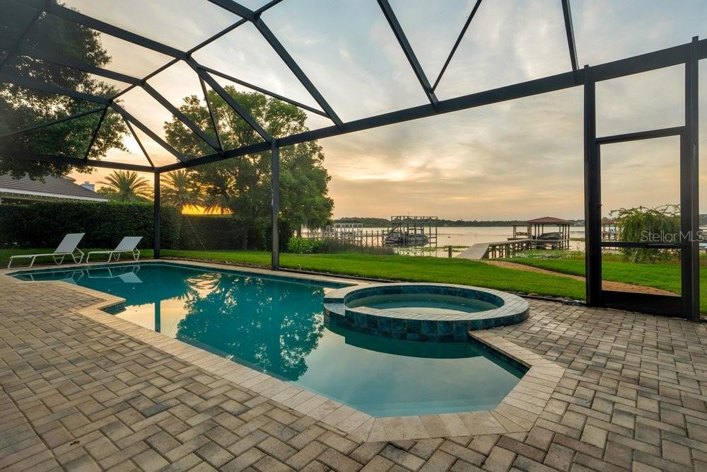 A screened-in patio features a swimming pool, a raised spa, and a lake view — 2503 BUTLER BAY DRIVE N, WINDERMERE, FL
