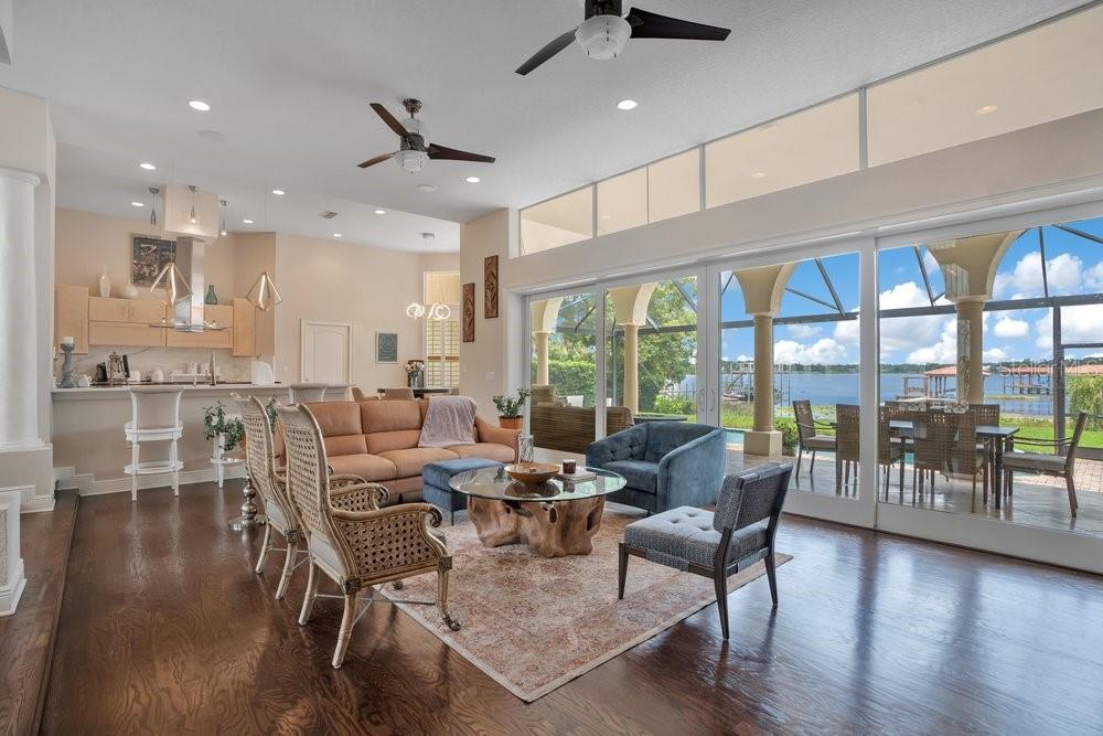 A living room with hardwood floors, a tan sofa, and large windows overlooking a lake — 2503 BUTLER BAY DRIVE N, WINDERMERE, FL