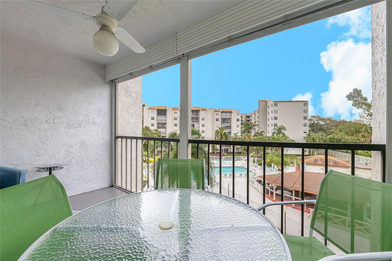 A screened-in balcony features a glass-top table, green chairs, a ceiling fan, and pool views — 3920 Inverrary Boulevard # C, Lauderhill FL 33319, LAUDERHILL, FL