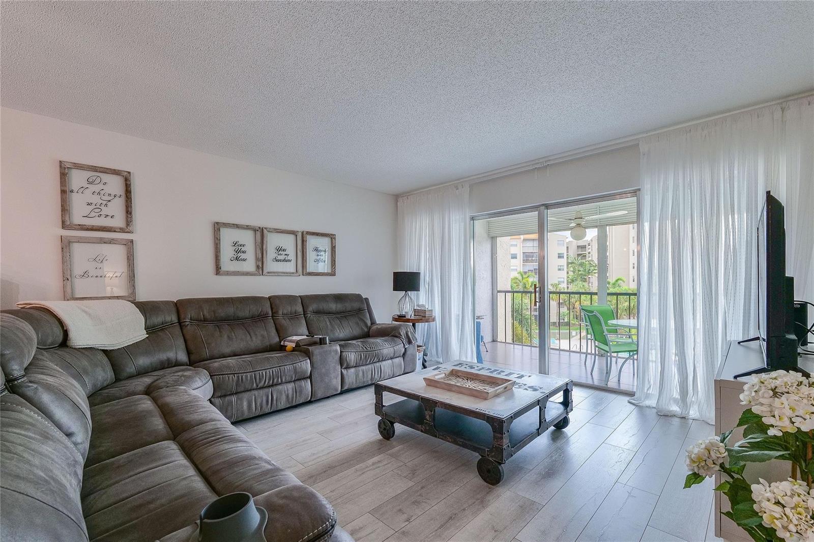A living room with a grey sectional sofa, coffee table, and sliding doors to a balcony — 3920 Inverrary Boulevard # C, Lauderhill FL 33319, LAUDERHILL, FL