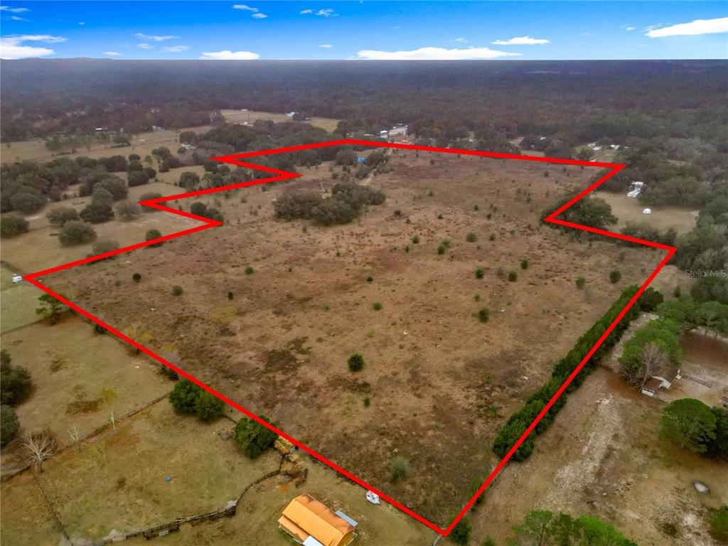 An aerial view shows a large, open, grassy lot outlined in red — 12521 SW HIGHWAY 484, DUNNELLON, FL