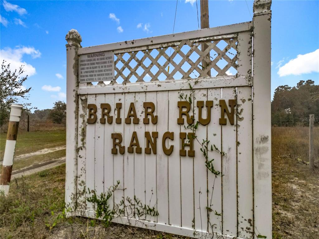 A white fence sign displays the name Briar Run Ranch in a grassy field — 12521 SW HIGHWAY 484, DUNNELLON, FL