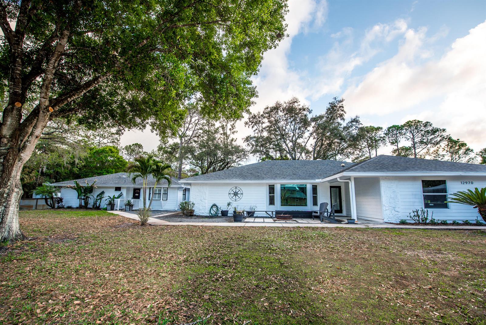 A white single-story house with a large tree and a patio in the front yard — 12970 179th Ct N, Jupiter FL 33478, JUPITER, FL