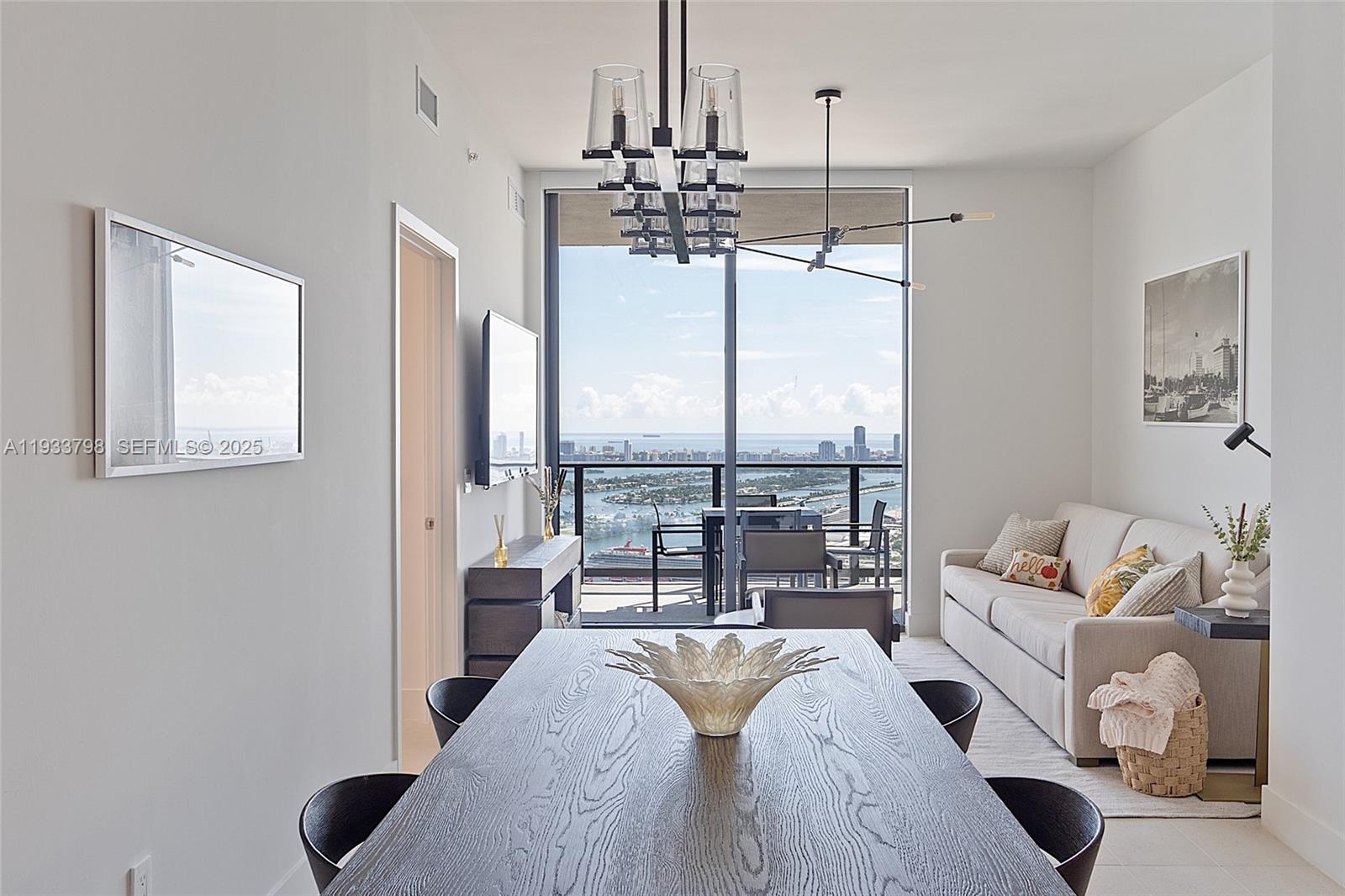 A modern dining and living area features a dark wood table, sofa, and balcony view — 159 NE 6th St # 5015, Miami FL 33132, MIAMI, FL